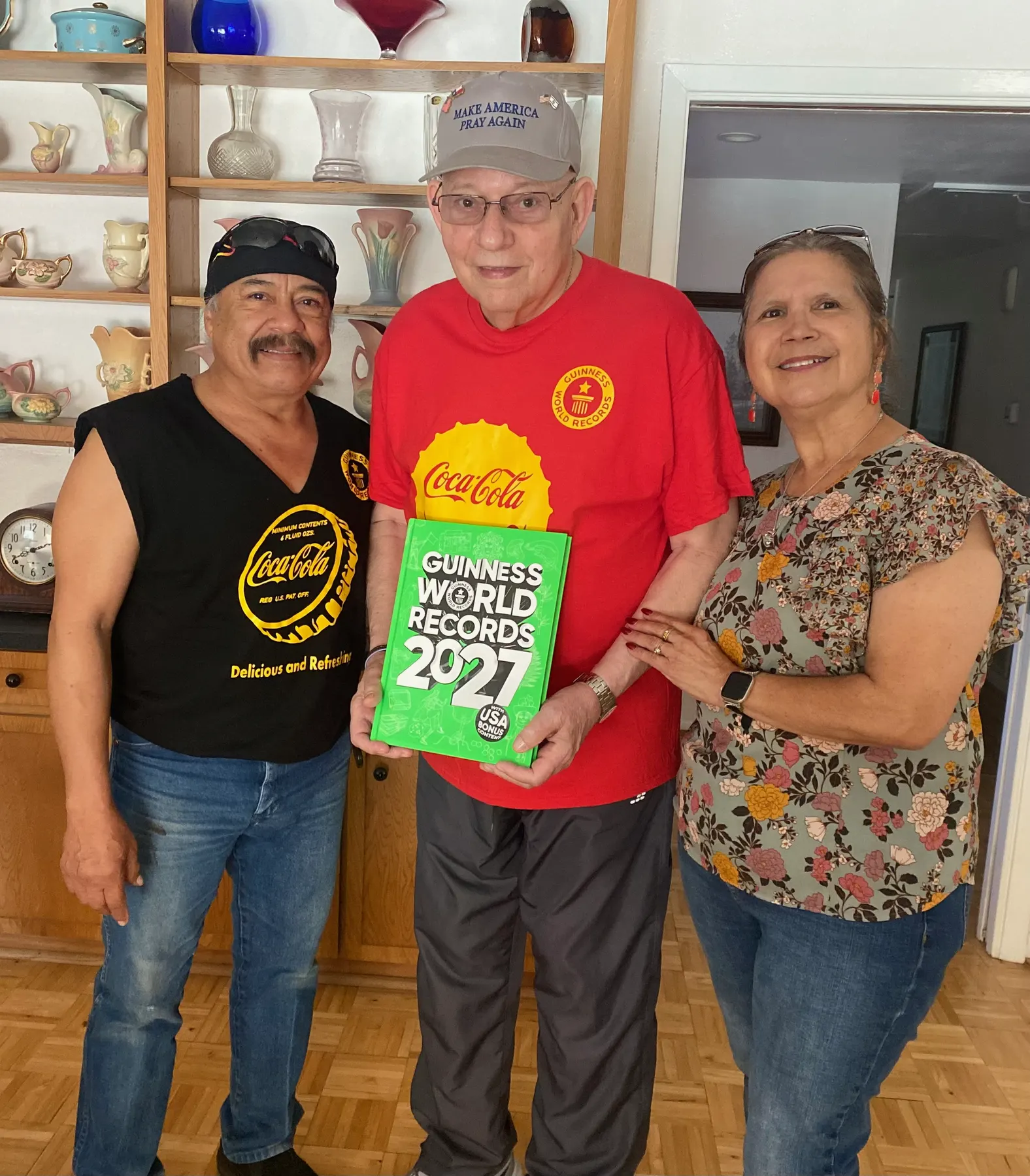 Bardo and Olga Cuellar with their friend Ron, holding his dedicated copy of Guinness World Records 2027