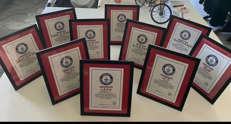 Framed, personalized Guinness World Records certificates lined up on a table, one for each person who helped the Cuellars set the record