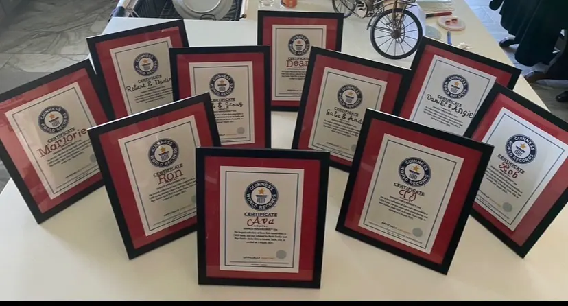 Framed, personalized Guinness World Records certificates lined up on a table, one for each person who helped the Cuellars set the record